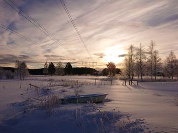 Scenic view of snow covered field against sky during sunset