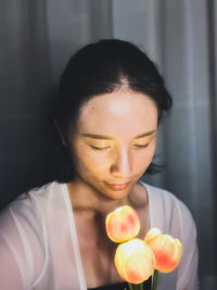 Close-up of young woman holding flower calmly at night 