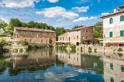 Old building by lake against sky