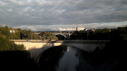 Arch bridge over river against sky in city