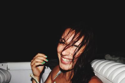 Close-up of smiling young woman holding camera at night