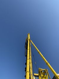 Low angle view of crane against clear blue sky