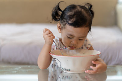 Close-up of girl eating food on table at home