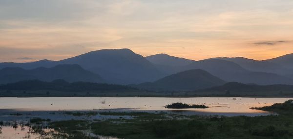 Scenic view of lake and mountains against sky at sunset