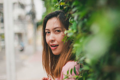 Portrait of smiling woman standing against plants