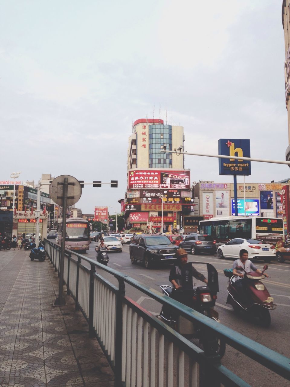 transportation, building exterior, architecture, built structure, mode of transport, sky, land vehicle, city, car, street, incidental people, city life, men, travel, cloud - sky, public transportation, day, road, person