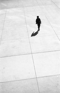 High angle view of man walking on footpath during sunny day