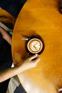 High angle view of hand holding coffee cup