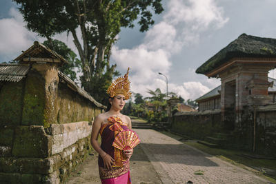 Thoughtful woman wearing traditional clothing standing outdoors