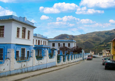 Road by buildings in city against sky