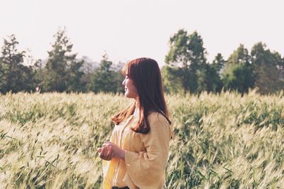 Side view of young woman standing on field