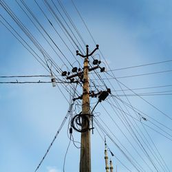 Low angle view of electricity pylon against blue sky