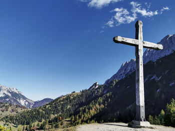 Low angle view of religious cross on rock against sky