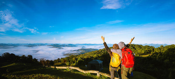 Rear view of man standing on mountain against sky