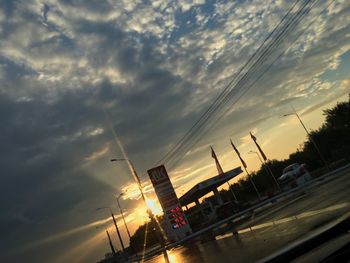 Cars on road against dramatic sky during sunset