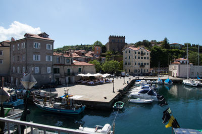 Boats moored in canal amidst buildings in city against sky