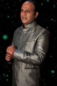 Portrait of young man standing against black background