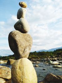 Close-up of stone stack on rock at beach against sky