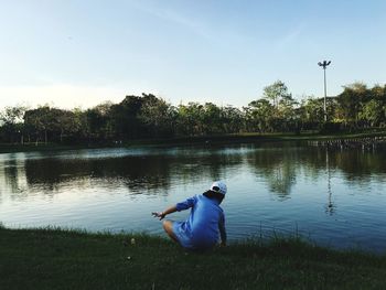 Man sitting in lake against sky