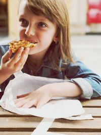 Close-up of girl eating pizza while sitting at table