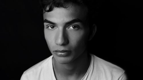 Close-up portrait of young man against black background