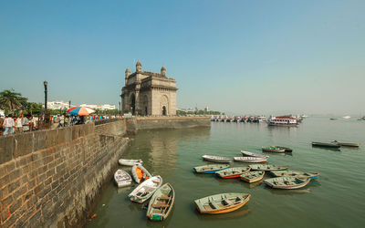 Boats moored in sea against gateway to india and clear sky