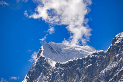 Low angle view of snowcapped mountains against blue sky