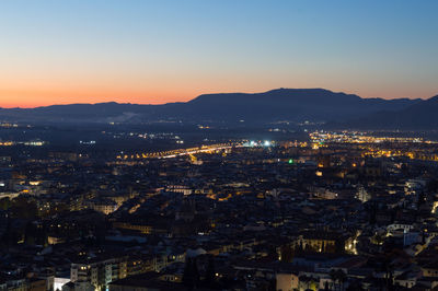 High angle view of illuminated cityscape against sky at sunset