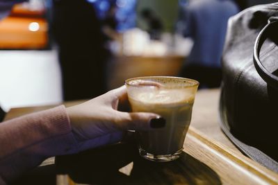 Close-up of hand holding wine glass on table