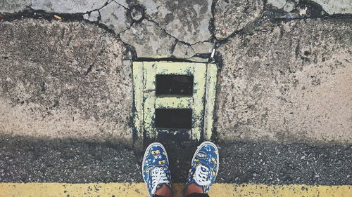 Low section of man standing by drainage on road