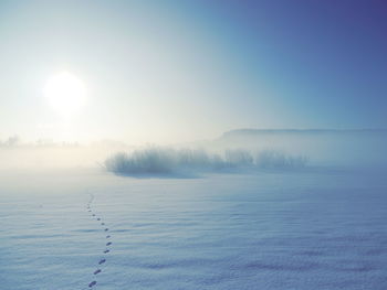 Scenic view of snow covered field against bright sky