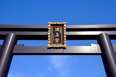 Low angle view of sign board against clear blue sky