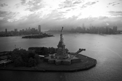 Statue in city against cloudy sky