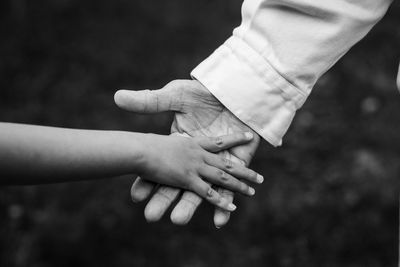 Close-up of father holding hand of daughter 