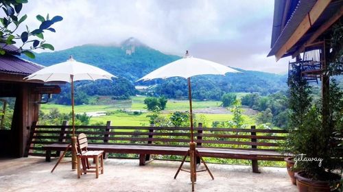 Empty chairs and mountains against cloudy sky