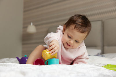 Close-up of girl playing with toys on bed at home