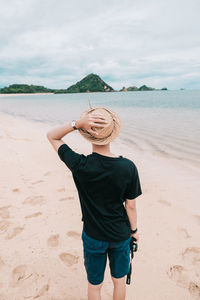 Rear view of men standing on shore at beach