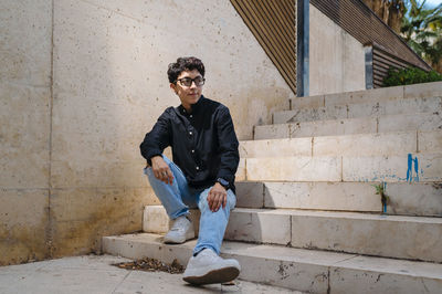 Young transgender person looking away while sitting on stairs outdoors.