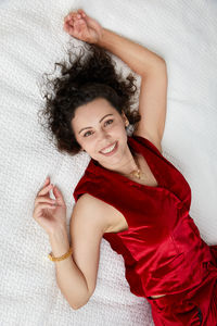 Portrait of smiling young woman lying down on bed