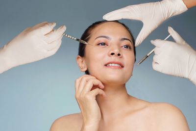 Close-up of doctor injecting syringe against white background