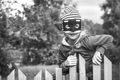 Portrait of boy standing against fence