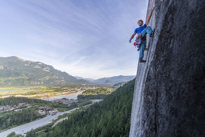 Man lead climbing granite squamish with background view of valley