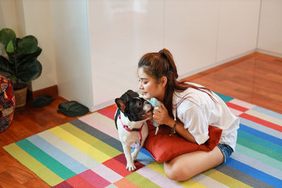 Woman with dog sitting on floor at home