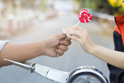 Close-up of hands holding red lollipop