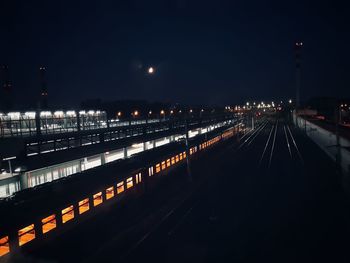 Illuminated railroad station against sky at night