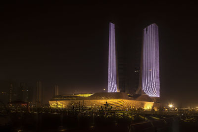 Illuminated modern buildings against sky at night