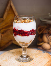 Cherry yoghurt parfait with crispy granola on top in a wine glass