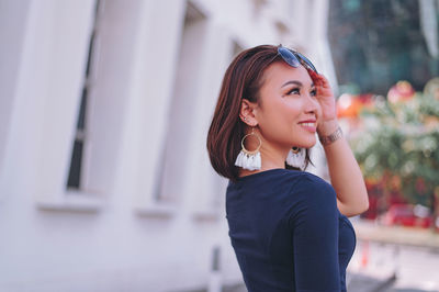 Portrait of smiling woman standing against blurred background