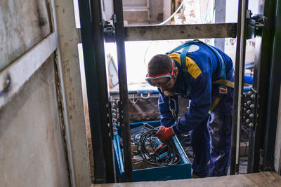 Caucasian worker in blue overalls picking up the tool after work