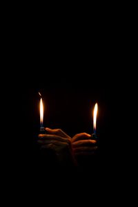 Cropped hands igniting lighters against black background